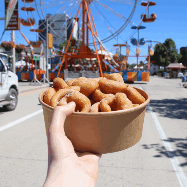Arm outstretched holding container full of donuts Arm outstretched holding container full of donuts